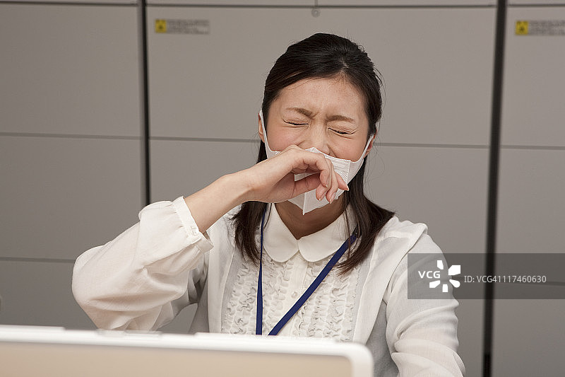 年轻女商人戴着口罩打喷嚏图片素材