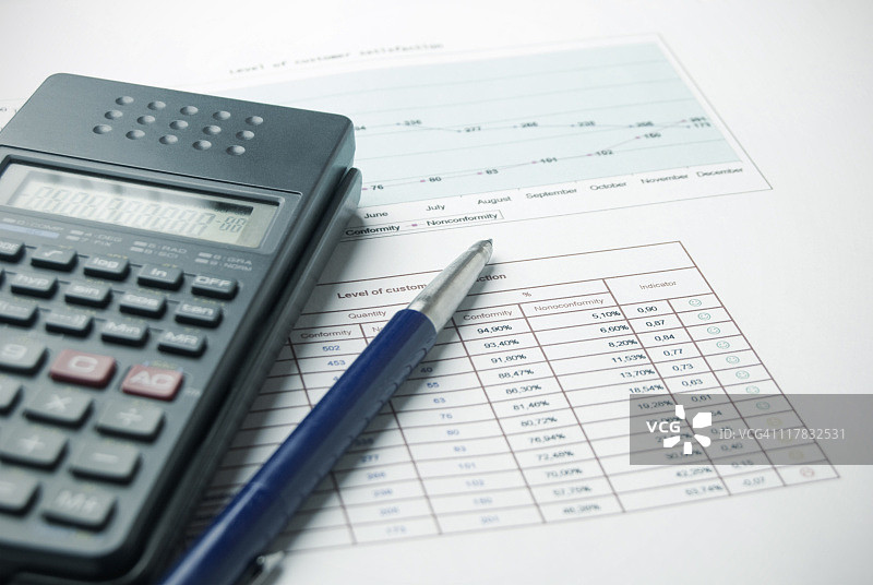 数据纸质文件上的计算器和笔图片素材