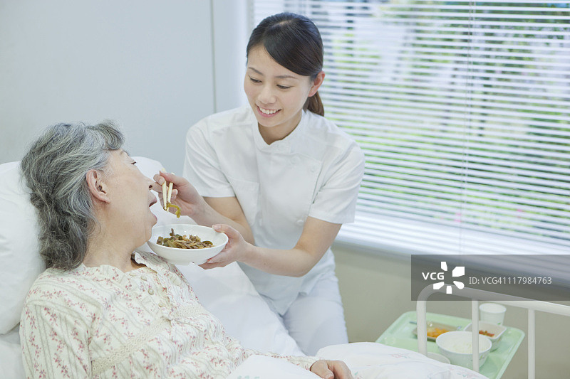 护士帮助老年妇女在床上吃饭,日本本州岛神奈川县图片素材