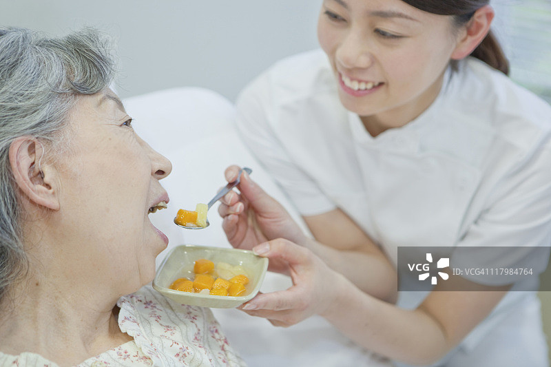 护士帮助老年妇女在床上吃饭,日本本州岛神奈川县图片素材
