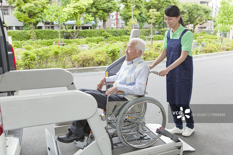 医护人员帮助坐在轮椅上的老人进入面包车，日本本州岛神奈川县图片素材