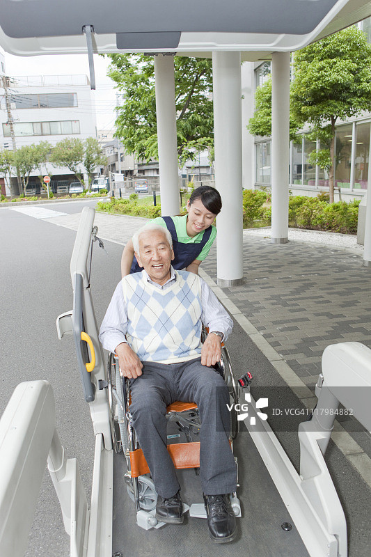 医护人员帮助坐在轮椅上的老人进入面包车，日本本州岛神奈川县图片素材