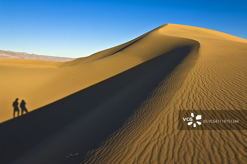 死亡谷沙丘上两人行走的剪影图片素材