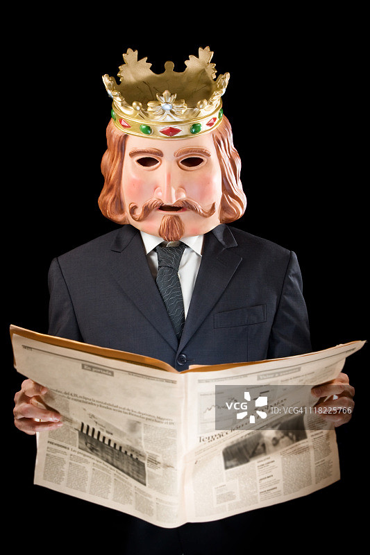 戴着国王面具阅读新闻的商人图片素材