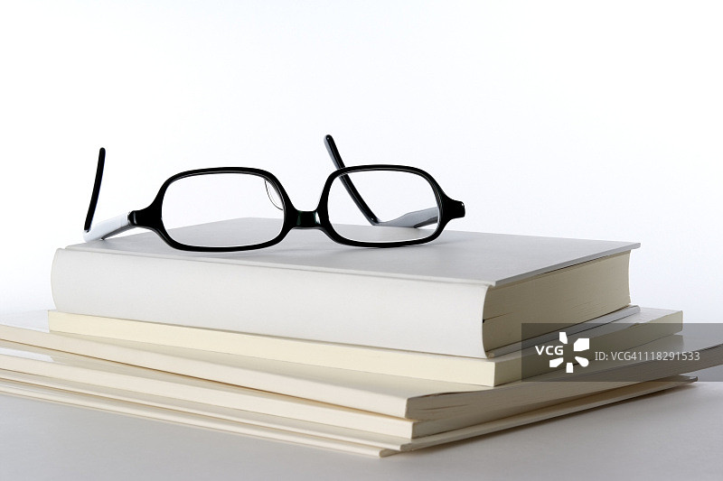 白色背景上堆叠的空白书籍和眼镜图片素材