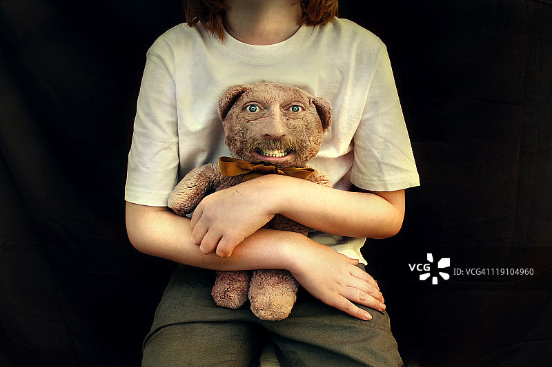 女孩抱着有着怪异人脸的泰迪熊图片素材
