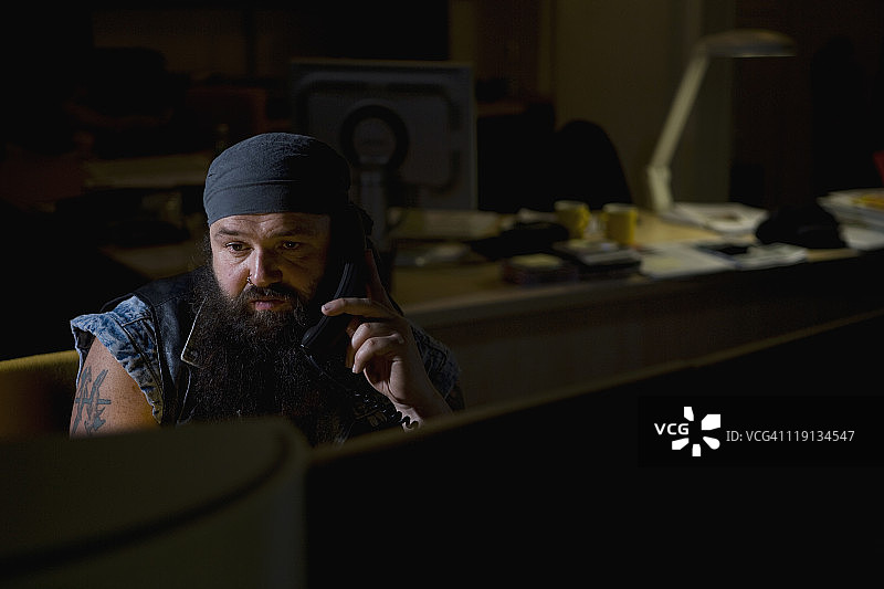 一位骑车人在黑暗的办公室里打电话图片素材