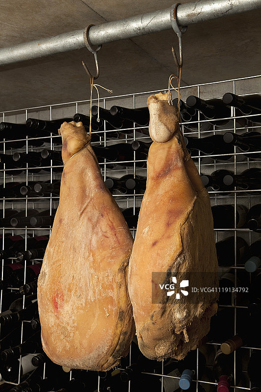 两条悬挂在地窖中的腌制火腿图片素材