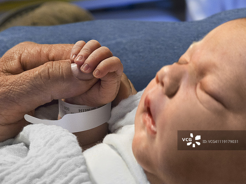 新生婴儿握着成人的拇指图片素材