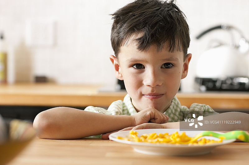 小男孩端着一盘奶酪通心粉图片素材