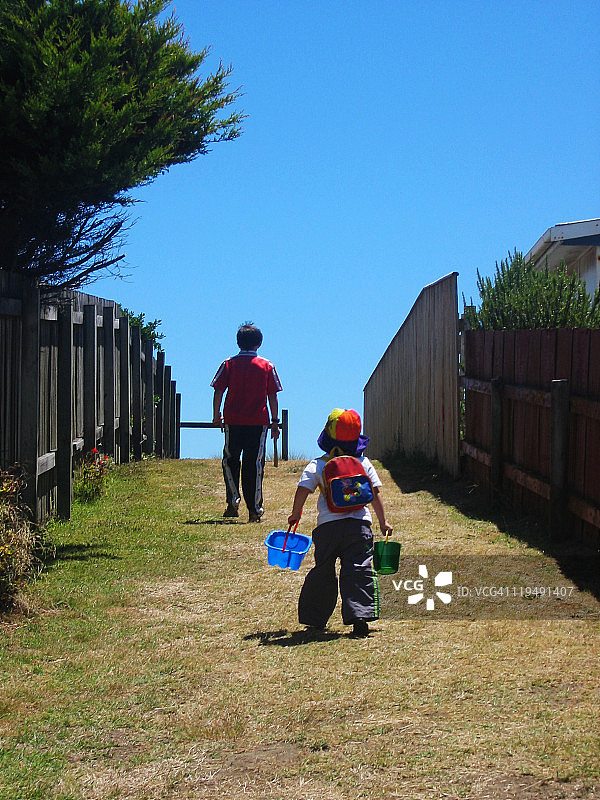 儿童提着水桶去海滩图片素材