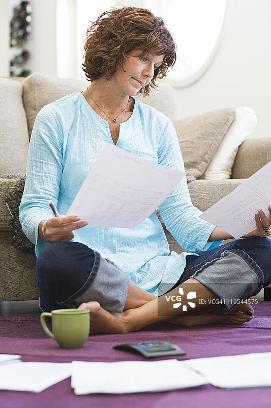 女人坐在地面上，面前放着账单图片素材