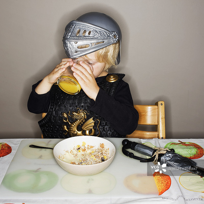 身穿盔甲套装正在喝果汁的男孩图片素材