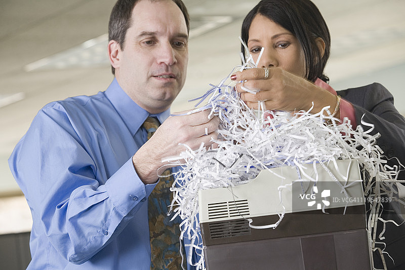 商务人士与西班牙裔女商人查看碎纸特写图片素材