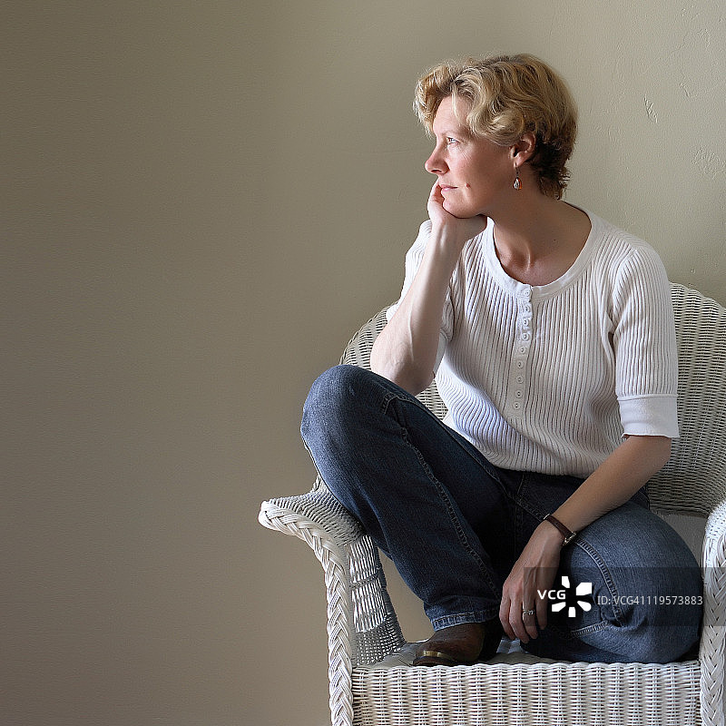 女人跪在白色柳条椅上图片素材