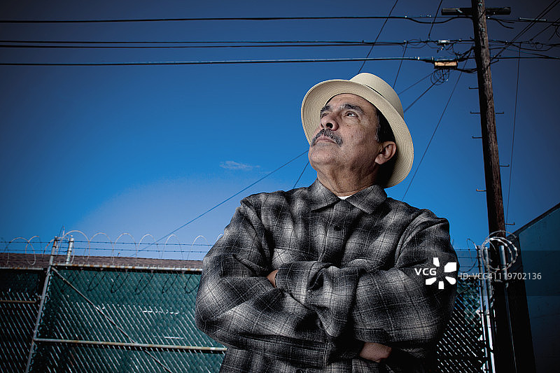 双手交叉向上看的西班牙裔男人图片素材