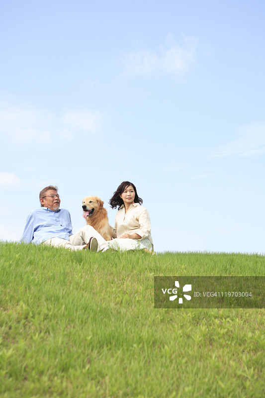 中年夫妇和狗坐在田野里图片素材
