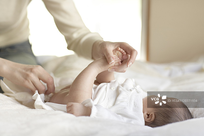 母亲在床上给宝宝换尿布图片素材