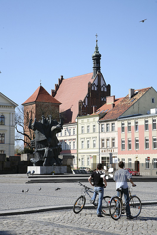 波兰城镇广场上骑自行车的男人们图片素材