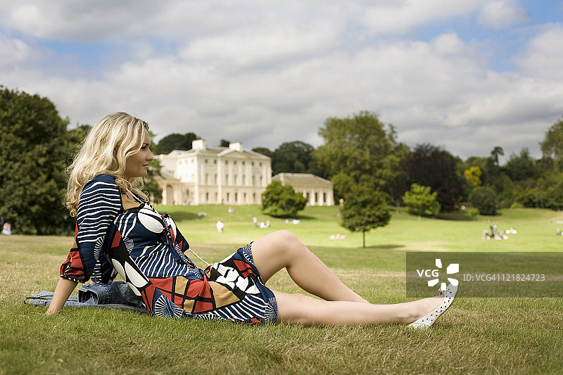 女人躺在伦敦汉普斯特德西斯肯伍德庄园前的草地上图片素材