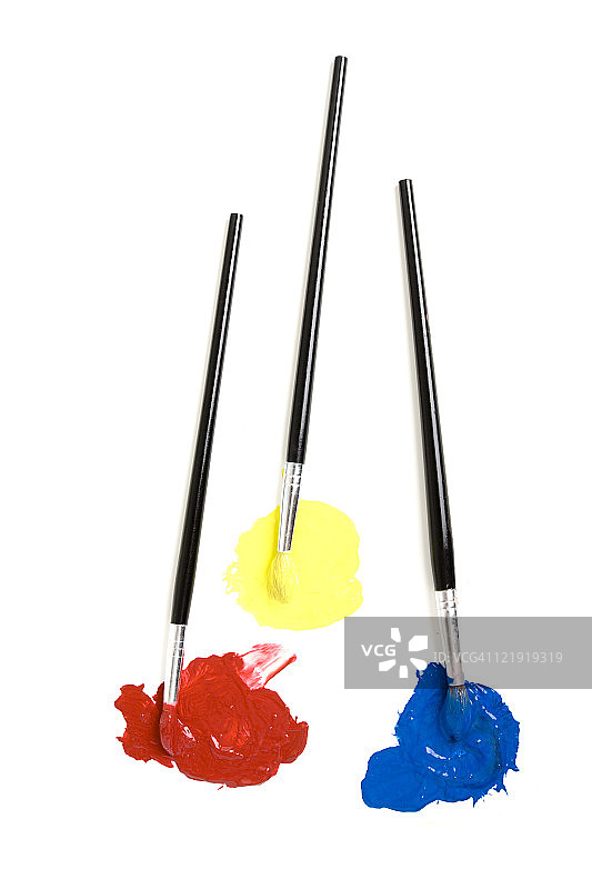 浸在红黄蓝颜料中的三把画笔图片素材