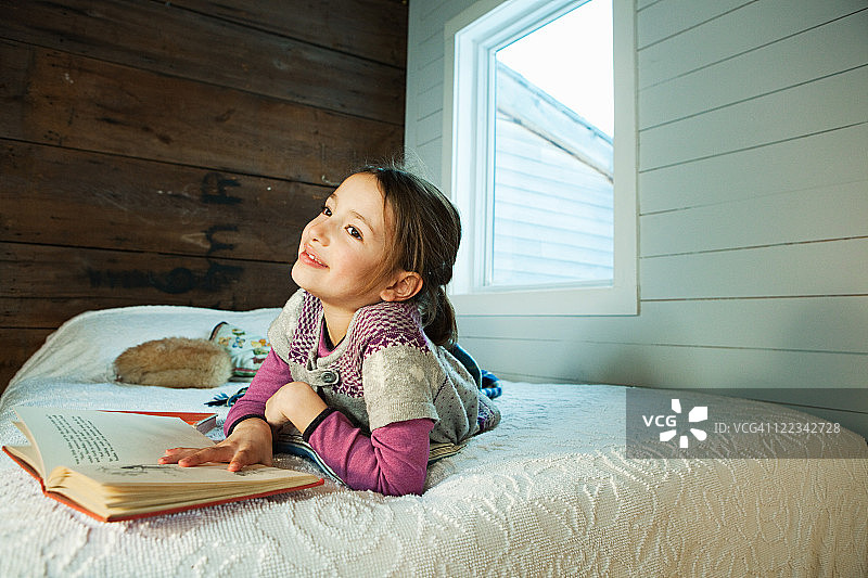 躺在床上看书的年轻女孩图片素材