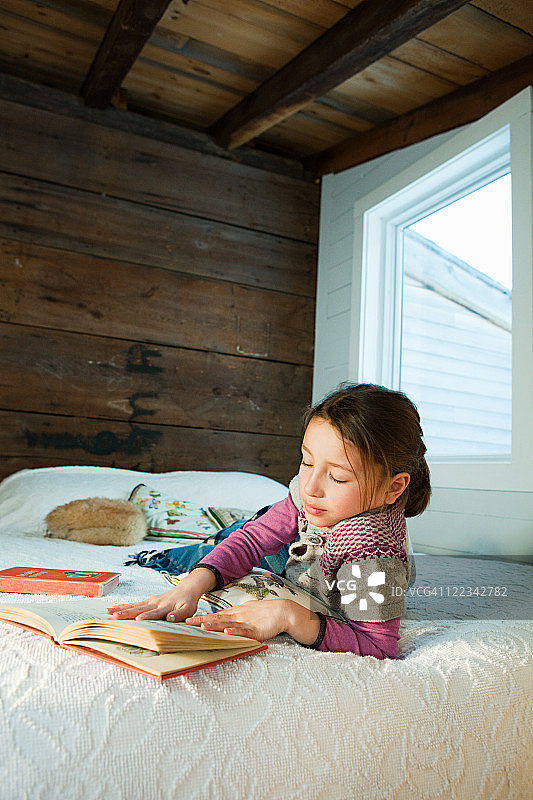 躺在床上看书的年轻女孩图片素材