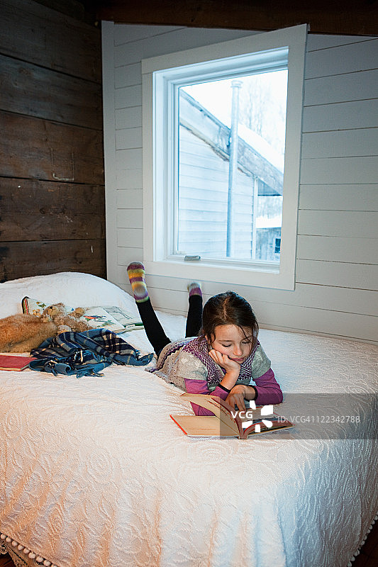 躺在床上看书的年轻女孩图片素材