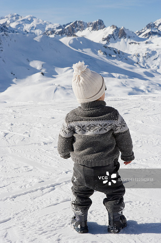 站立着看着雪山中的男孩图片素材
