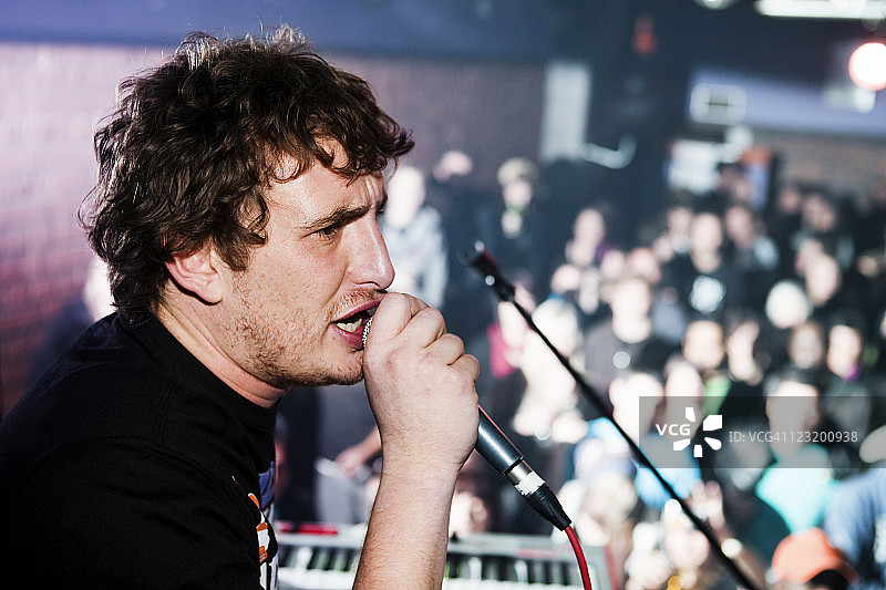 年轻的演讲者或歌唱者在观众面前激情演讲图片素材