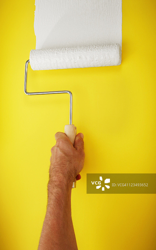 黄色墙面上的油漆滚筒图片素材