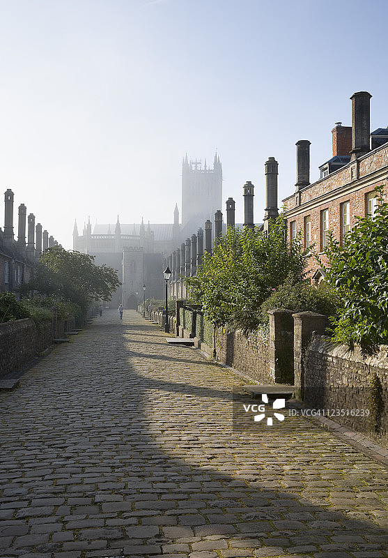 雾蒙蒙的早晨，牧师公馆的排屋，远处是萨默塞特郡韦尔斯镇的韦尔斯大教堂图片素材