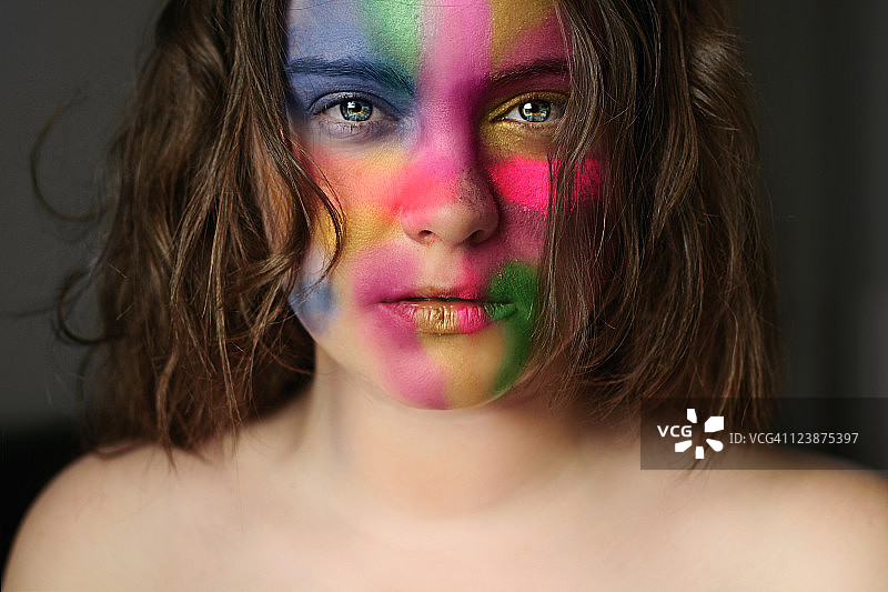 面部涂有鲜艳色彩的年轻女子肖像图片素材