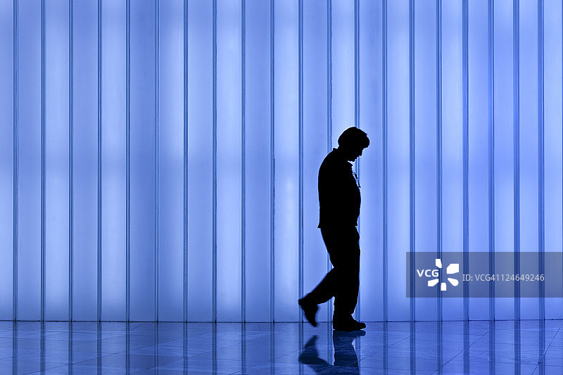 现代灯光墙前沮丧的男人剪影图片素材