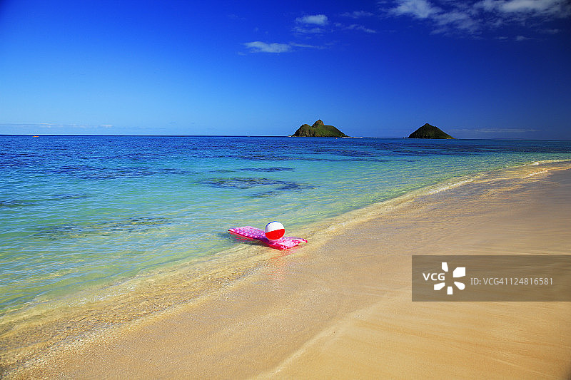 夏威夷瓦胡岛拉尼凯海滩粉色充气筏和沙滩球，背景是莫库鲁阿群岛图片素材