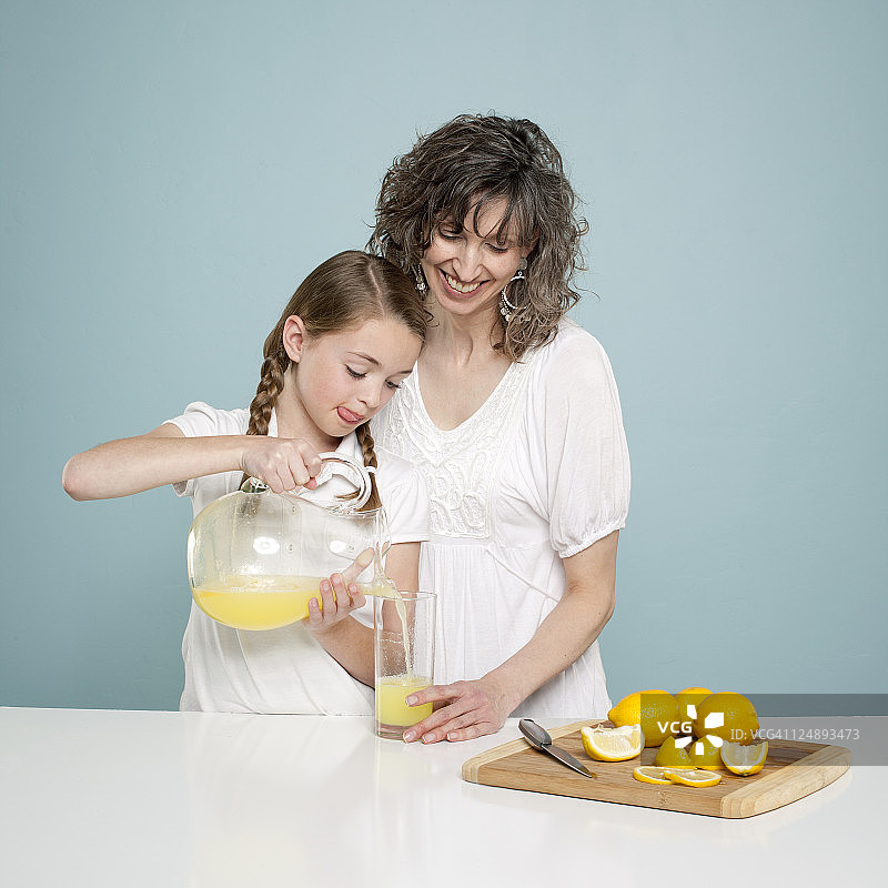 母亲协助女儿倒柠檬水的影棚照片图片素材