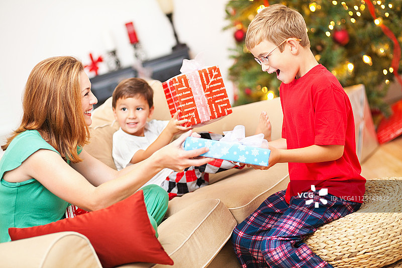 圣诞节早晨母亲给兴奋的儿子送礼物图片素材