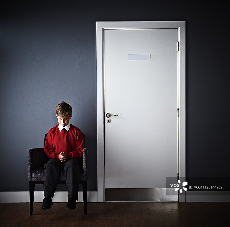 坐在校长办公室前的小男孩图片素材