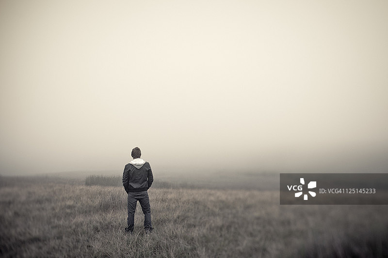 眺望雾气沼泽地的年轻男人图片素材