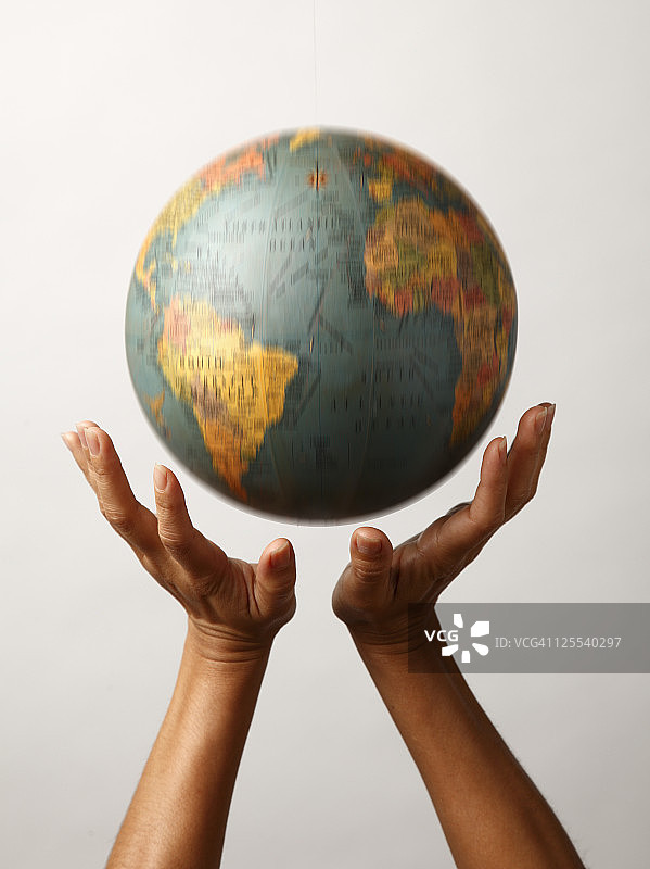 两只手在移动的地球仪下图片素材