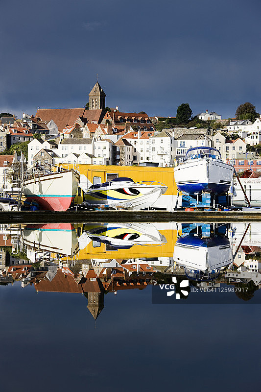 海峡群岛格恩西岛圣彼得港及港口边的船只停靠在旱坞上，倒映在模型船池塘中图片素材
