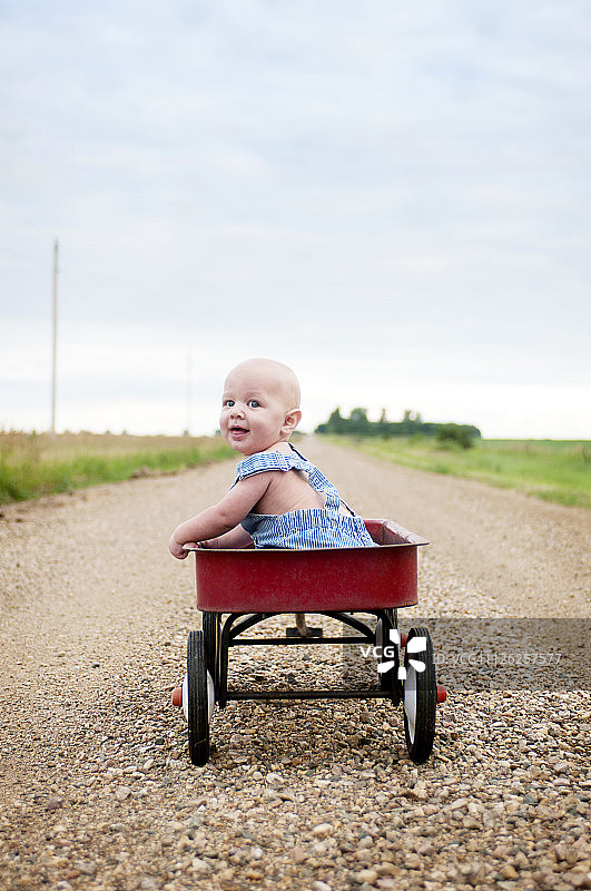 坐在红色四轮车里的男婴图片素材
