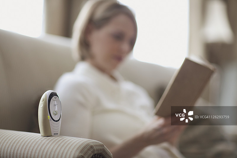 母亲通过婴儿监视器阅读图片素材