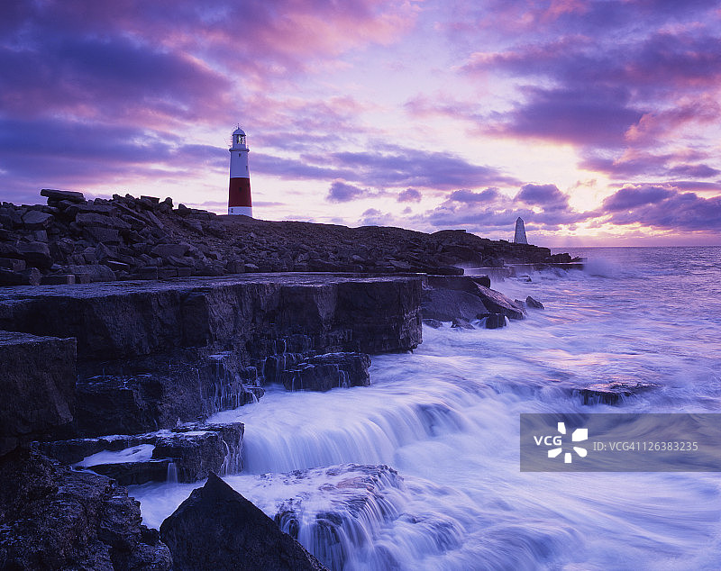 多塞特波特兰比尔灯塔附近海浪拍打岩石的黄昏天空图片素材