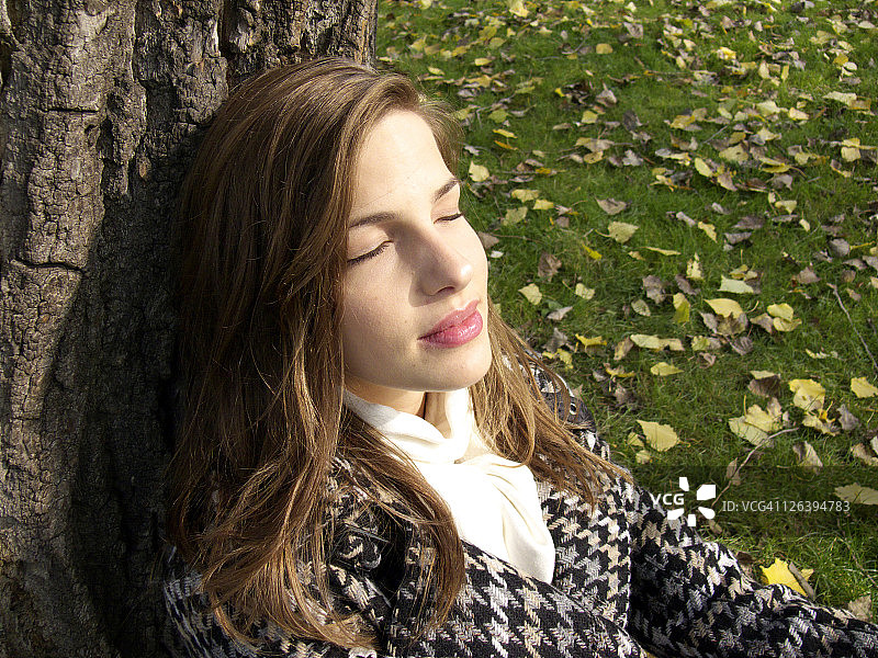 坐在树干上微笑的年轻女子的特写镜头图片素材