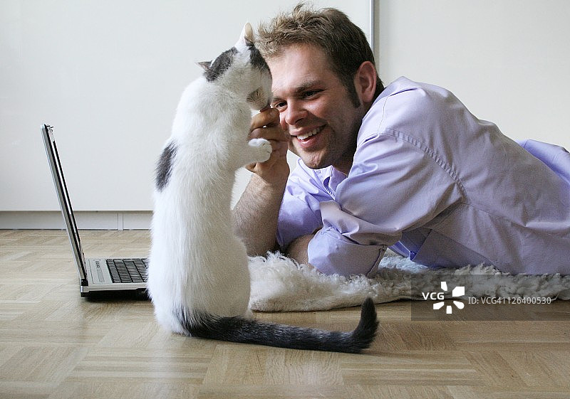 年轻男人喂猫的侧面照图片素材