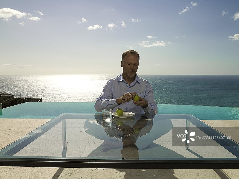 男人在泳池边削苹果图片素材