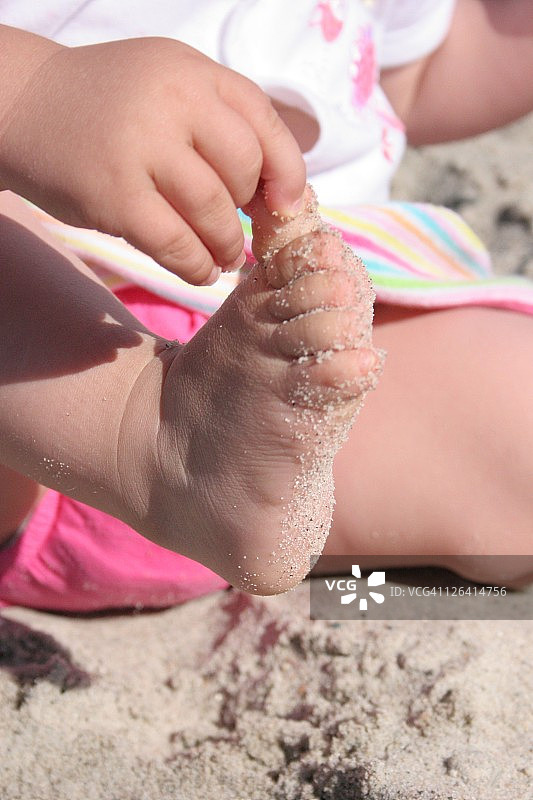 在沙滩上玩沙子的女孩的中间部分图片素材