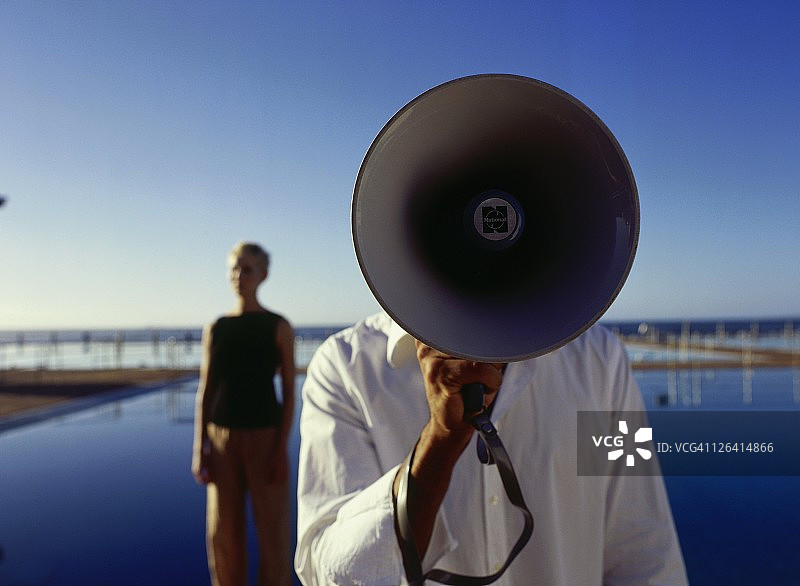 男子使用扩音器，背景站着一名女子的特写镜头图片素材