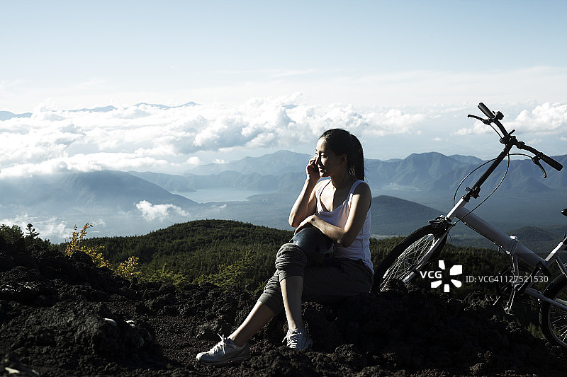 在山区用手机聊天的年轻女人图片素材